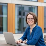 Frau sitzt mit Laptop an einem Tisch